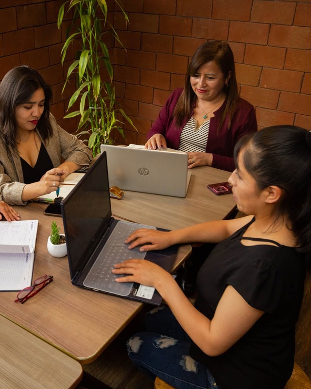 Sandra Cárdenas sentada en una mesa de trabajo junto a su comunidad
