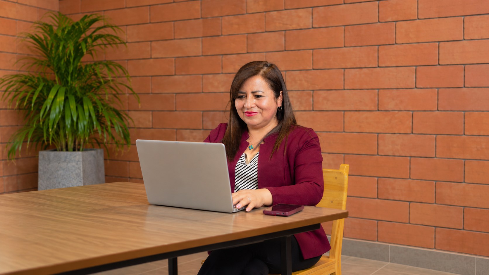 Sandra Cárdenas sentada en una mesa, trabajando en su laptop